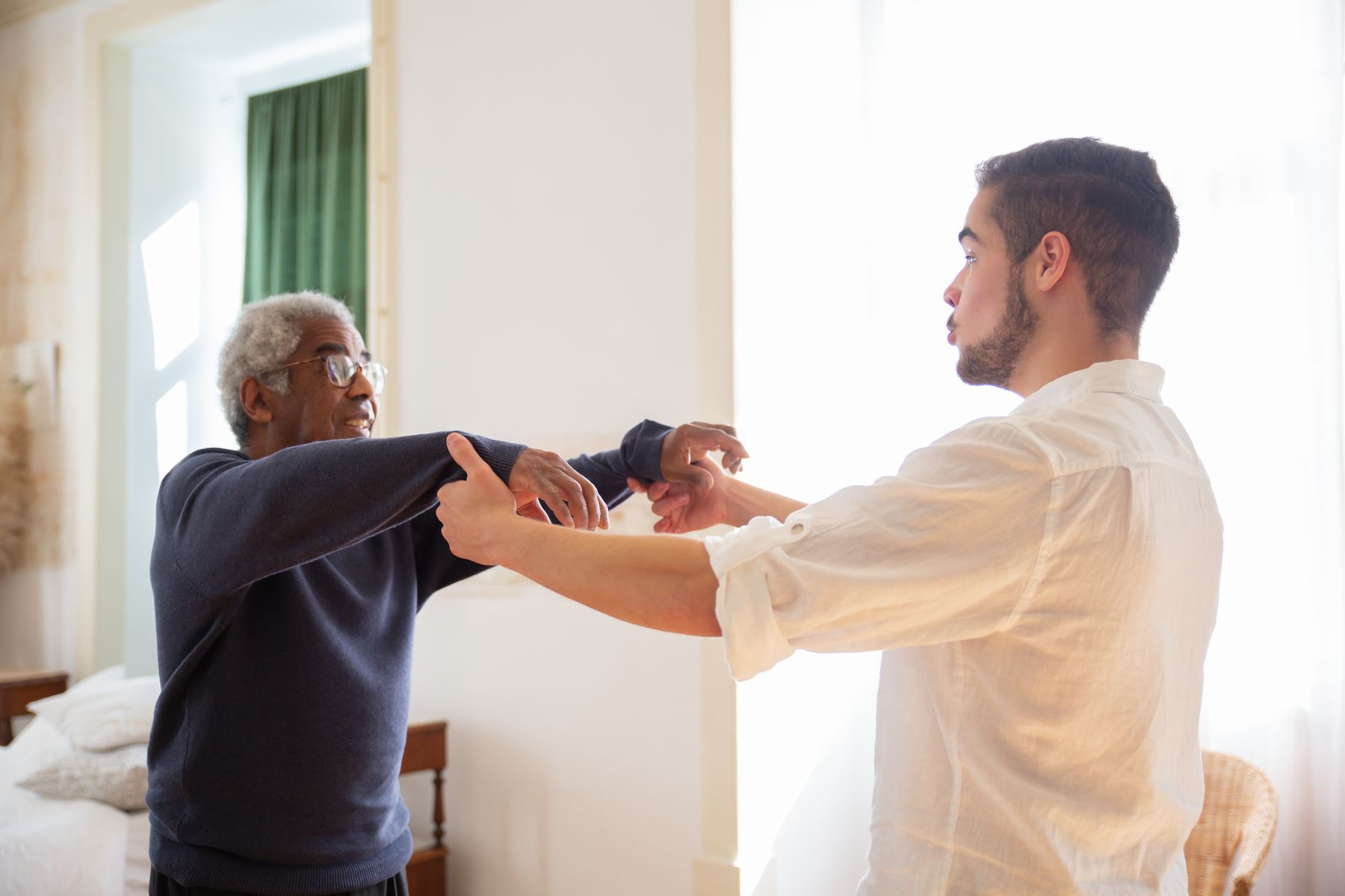 A companion helping an older man with a daily movement at home