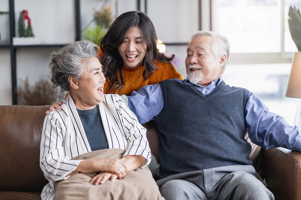 Adult children laughing with their parents on the sofa at home
