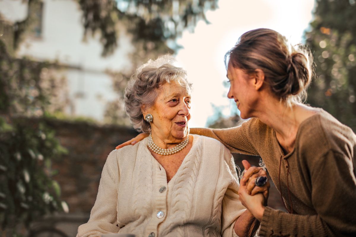 An older woman sharing a warm conversation with a companion outdoors