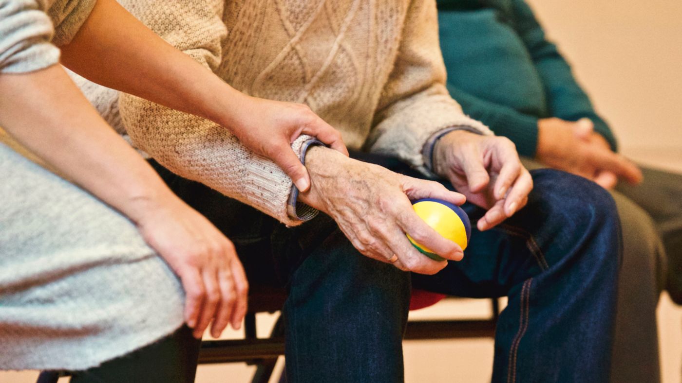 A companion supporting an older adult during a gentle activity